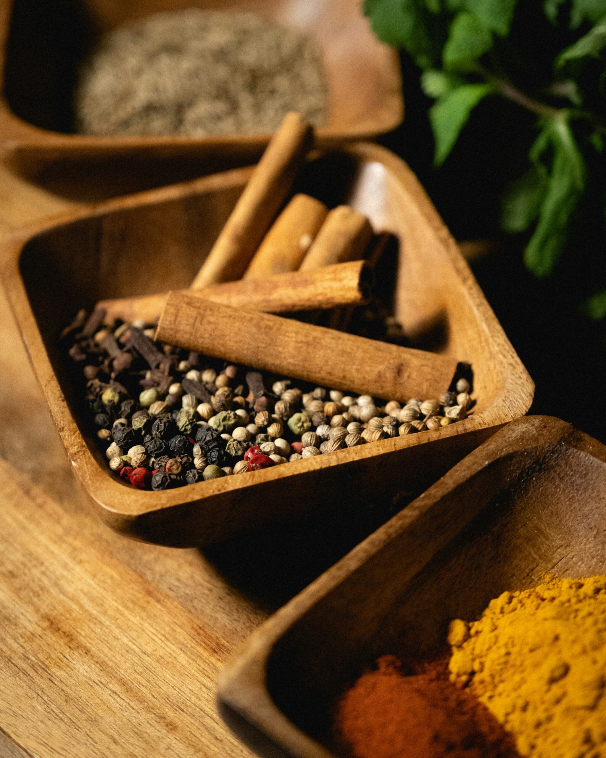 Cinnamon sticks and mixed peppercorns in wooden bowls