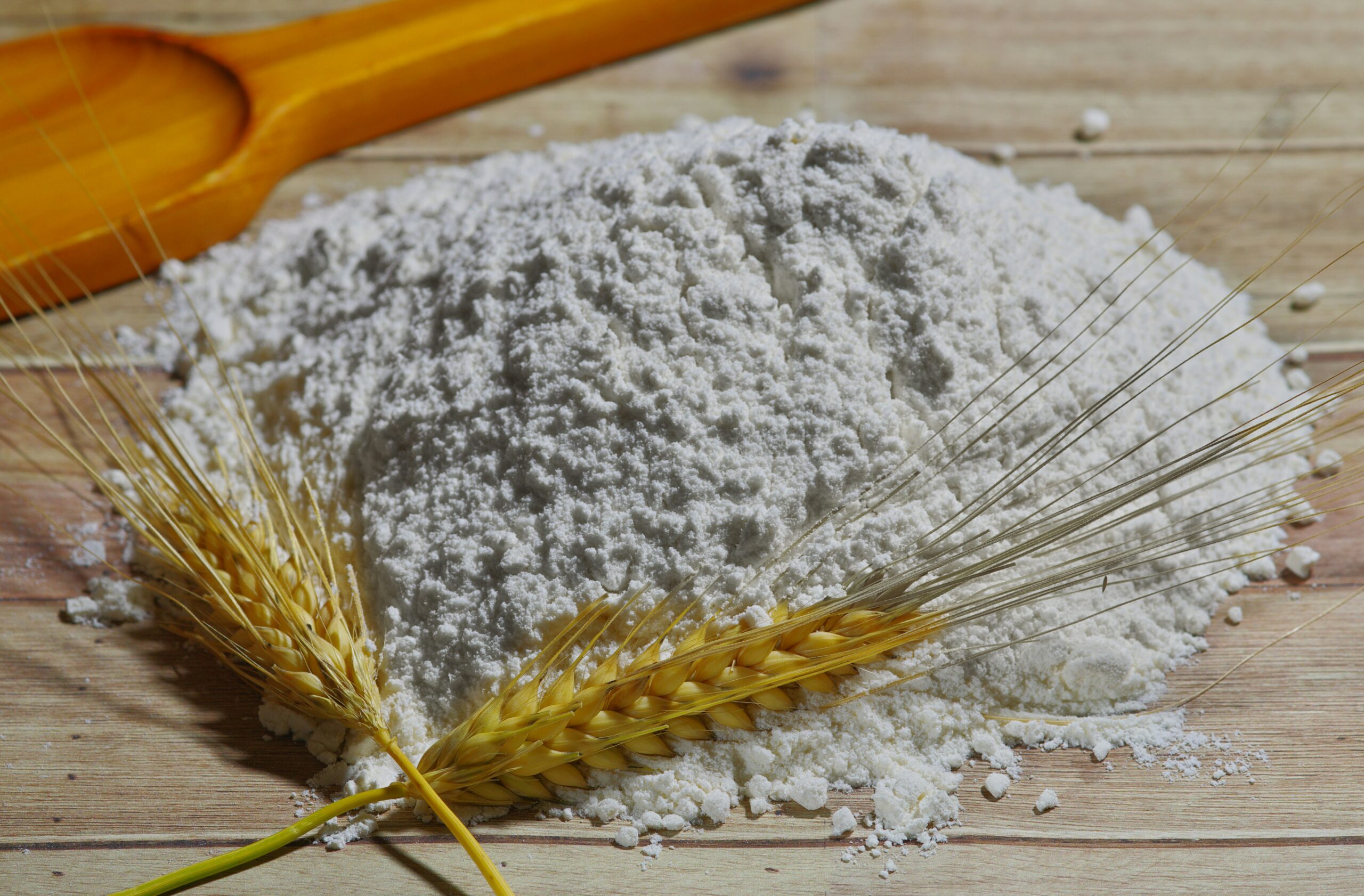 Wheat flour on a wooden surface with wheat ears